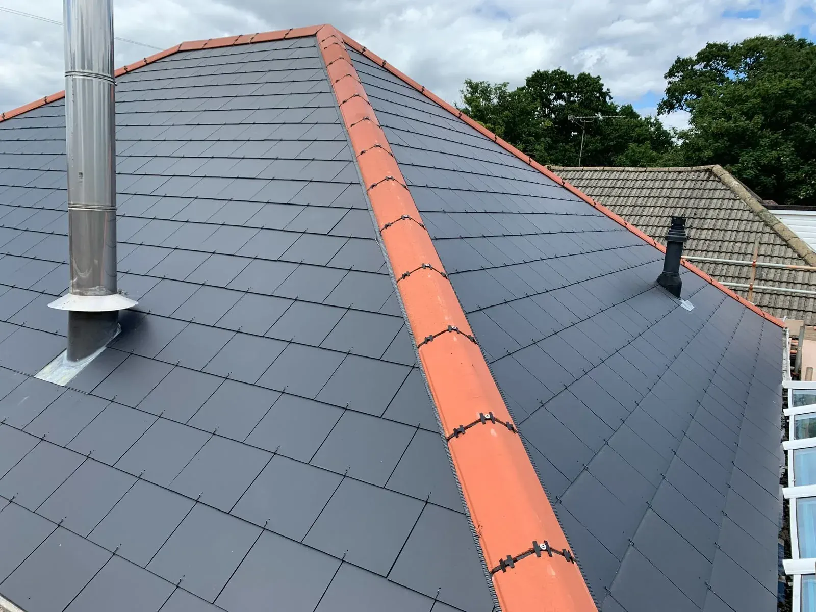 Slate roof with clay ridge tiles and a new flue by DJW Roofing & Leadwork
