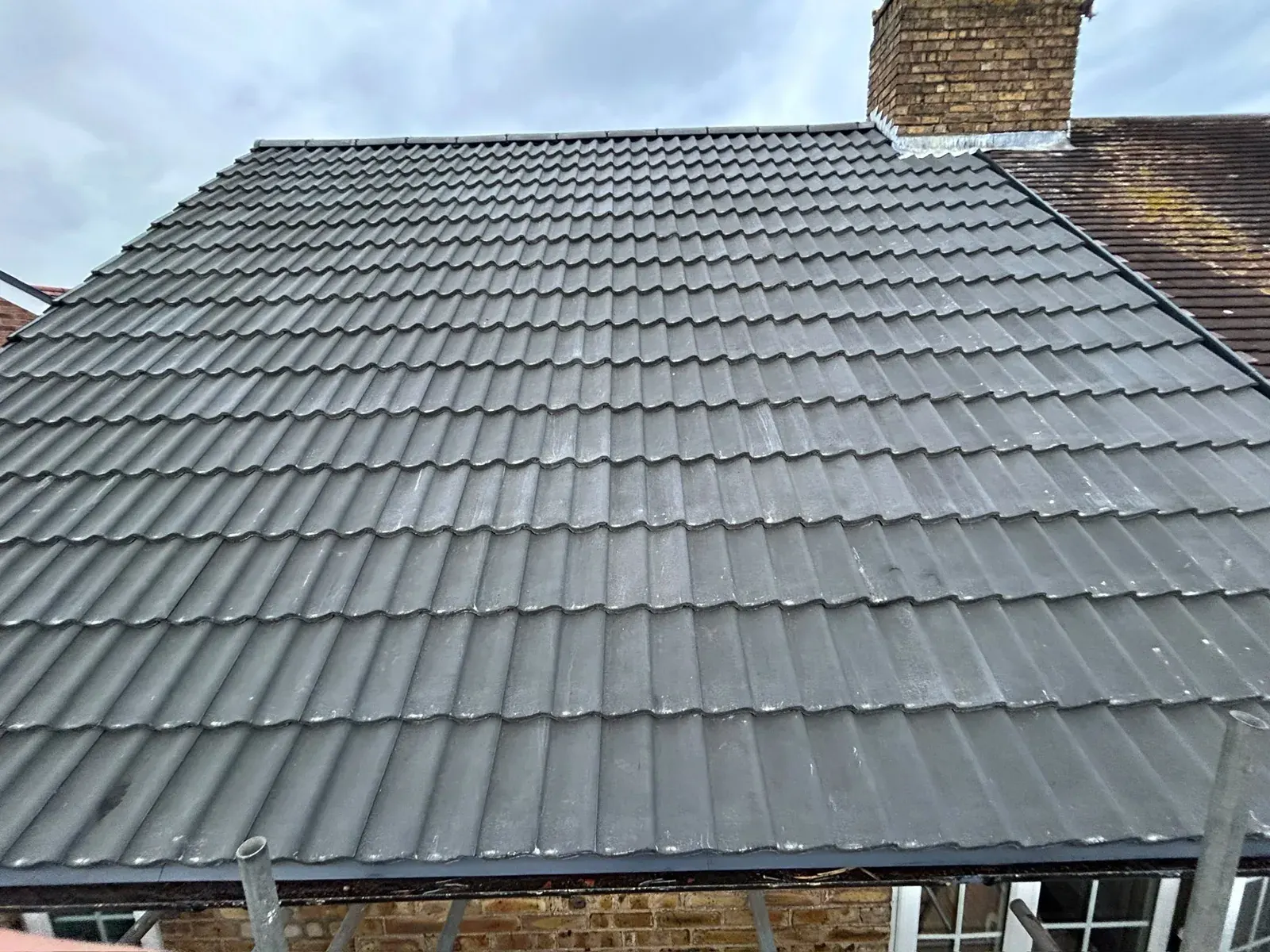 Completed grey tile re-roof with a chimney by DJW Roofing & Leadwork
